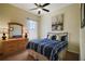 Cozy bedroom featuring a double bed with a ceiling fan, dresser with a mirror and a window at 11041 Se 169Th Pl, Summerfield, FL 34491