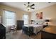 Well-lit bedroom with two windows, a ceiling fan, flower wall art, and antique furniture at 11041 Se 169Th Pl, Summerfield, FL 34491
