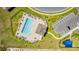 An aerial view shows a community pool with lounge chairs and a nearby parking area and playground at 1179 Tyler Loop, Winter Haven, FL 33884