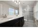 Bright bathroom with dual sinks, black cabinetry, a modern glass shower, and a window at 12180 Sonnet Ave, Orlando, FL 32832