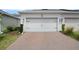 Two-car white garage with brick paver driveway, and manicured landscaping, creating curb appeal at 12180 Sonnet Ave, Orlando, FL 32832
