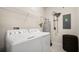 Bright laundry room featuring a washing machine, dryer, water heater, and shelving at 12180 Sonnet Ave, Orlando, FL 32832