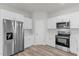 Well-lit kitchen featuring white cabinets, stainless steel appliances, and wood-look floors at 13673 Sw 43 Cir, Ocala, FL 34473
