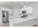 A modern kitchen features stainless steel appliances, white cabinetry and island with quartz countertop at 13673 Sw 43 Cir, Ocala, FL 34473