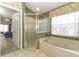 Bathroom featuring a tiled soaking tub, and a glass-enclosed shower with natural light from window at 14021 King Sago Ct, Orlando, FL 32828