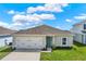 Inviting single-story home with a manicured lawn, a two-car garage, and a charming light blue front door at 1511 Finnigan Cir, Haines City, FL 33844