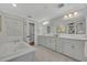 Bathroom features dual sinks, white cabinets, a soaking tub, and decorative art at 1633 Pine Ave, Winter Park, FL 32789