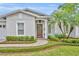 Inviting entryway showcasing a wood front door with decorative wreath, framed by trimmed hedges and a brick walkway at 1633 Pine Ave, Winter Park, FL 32789