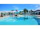 Community pool with splash pad, sun umbrellas, pergola, lounge seating, and mature palm trees at 1876 Nice Ct, Kissimmee, FL 34747