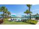 Community pool with lounge seating and sun umbrellas surrounded by tropical landscaping and mature palms at 1876 Nice Ct, Kissimmee, FL 34747