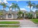 Charming single-story home featuring lush tropical landscaping, a brick driveway, and a stylish gray and white color scheme at 2218 Ridgewind Way, Windermere, FL 34786