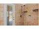 Luxurious walk-in shower with travertine tile, a modern showerhead, and glass door access to the patio at 2218 Ridgewind Way, Windermere, FL 34786