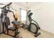 Carpeted exercise room featuring a multi-station home gym, elliptical machine, and bright natural light from a large window at 30413 Plymouth Creek Cir, Sorrento, FL 32776