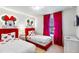 Fun ' bedroom featuring twin beds with Mickey Mouse decor, themed lighting, and bright red curtains at 3966 Lana Ave, Davenport, FL 33897