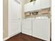 Well-organized laundry room features wood flooring, a washer, dryer, and storage cabinets at 408 Almeria Ct, Winter Springs, FL 32708
