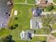 Overhead view of pristine lawns, sandy beach, and a home with a swimming pool bordering a serene lake at 49 Interlaken Rd, Orlando, FL 32804
