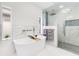 Bright bathroom featuring a soaking tub, glass enclosed shower with rainfall head and marble tile at 49 Interlaken Rd, Orlando, FL 32804