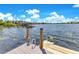 Lake dock view featuring a ladder, wooden posts, and a peaceful lakeside setting under a sunny sky at 49 Interlaken Rd, Orlando, FL 32804