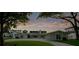 Exterior view of a well-maintained home with a manicured lawn and a long driveway under a colorful sky at 49 Interlaken Rd, Orlando, FL 32804