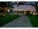 Front exterior showcasing a sprawling lawn, long driveway, and elegant lighting under a vibrant sunset backdrop at 49 Interlaken Rd, Orlando, FL 32804
