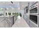 A modern kitchen with gray cabinets, a waterfall island, and stainless steel appliances gleams with natural light at 49 Interlaken Rd, Orlando, FL 32804