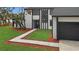 Modern home exterior with black and white trim, a well-manicured lawn, and a concrete walkway leading to the front door at 4940 Spring Run Ave, Orlando, FL 32819