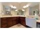 Bathroom featuring a vanity with cherry wood cabinets, neutral countertops, and large mirrors at 5007 Belted Kingfisher Dr, Oxford, FL 34484