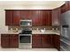 Contemporary kitchen with dark wood cabinets, granite countertops, and stainless steel appliances at 5007 Belted Kingfisher Dr, Oxford, FL 34484