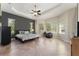 Spacious primary bedroom with tray ceilings and tiled floors, filled with natural light from many windows at 5007 Belted Kingfisher Dr, Oxford, FL 34484