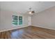 Well-lit living area with wood-style flooring, a ceiling fan and a large window at 57 Pine Trace Crse, Ocala, FL 34472