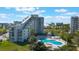 Condo exterior featuring a pool, nearby businesses, well-maintained landscaping and clear blue skies at 6165 Carrier Dr # 2001, Orlando, FL 32819