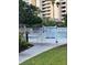 Community pool with white picket fence, warning signs, and views of the building and palm trees at 6165 Carrier Dr # 3104, Orlando, FL 32819