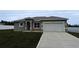 A single-story home featuring a two-car garage and well-manicured front lawn, showcasing its curb appeal at 6345 Sw 155Th Pl, Ocala, FL 34473