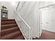 Carpeted stairway with white railing and trim with door leading to the upper level at 901 S Atlantic Ave # 3, Ormond Beach, FL 32176
