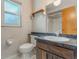 Traditional bathroom features a window, toilet, and vanity with a sink and wood cabinets at 610 Palomas Ave, Ocoee, FL 34761