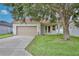 Single-story home boasting a two-car garage, lush lawn, and mature trees at 14717 Royal Poinciana Dr, Orlando, FL 32828