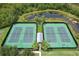 Aerial view of well-maintained tennis courts with a gazebo, surrounded by greenery and a pond at 14717 Royal Poinciana Dr, Orlando, FL 32828