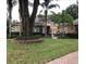 Stucco home with a barrel tile roof, mature landscaping, and a charming patio with an orange umbrella at 2108 Northumbria Dr, Sanford, FL 32771