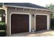 Two-car garage featuring dark wood doors, decorative lighting, and manicured landscaping at 2108 Northumbria Dr, Sanford, FL 32771