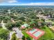 Aerial view of community, showcasing a tennis court, pool, parking, and surrounding mature trees at 4060 E Maryland Pl, Casselberry, FL 32707