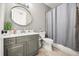 Bathroom featuring a gray vanity, round mirror, toilet, and shower with curtain at 1316 Lake Baldwin Ln, Orlando, FL 32814