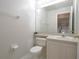 Well-lit half-bathroom with tiled floor, toilet, sink with vanity, and a large mirror with a view to laundry area at 14433 Huntingfield Dr, Orlando, FL 32824