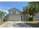Inviting two-story home featuring a two car garage, mature landscaping and a welcoming facade at 14433 Huntingfield Dr, Orlando, FL 32824
