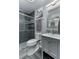 Modern bathroom featuring a glass shower with decorative tile, gray walls, and gray vanity at 1448 Lambert St, Deltona, FL 32725