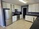 The kitchen features white cabinets, black countertops, stainless steel appliances, and tile flooring at 2018 Knollcrest Dr, Clermont, FL 34711