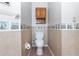 Small bathroom with a standard toilet, cabinet, and decorative wallpaper trim featuring travel-themed designs at 2621 Ardon Ave, Orlando, FL 32833