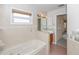 Bright bathroom with a tub, a vanity, a window, and neutral tile, creating a serene spa-like atmosphere at 2621 Ardon Ave, Orlando, FL 32833