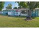Charming backyard featuring a deck, lush lawn, mature tree and sunroom, perfect for outdoor enjoyment at 3 Poinsettia Dr, Debary, FL 32713