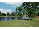 Scenic backyard featuring a tranquil lake, lush green grass, mature trees, and a chain-link fence at 3 Poinsettia Dr, Debary, FL 32713