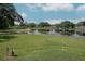 Expansive backyard with a tranquil lake view, lush green lawn, and mature trees under a blue sky at 3 Poinsettia Dr, Debary, FL 32713